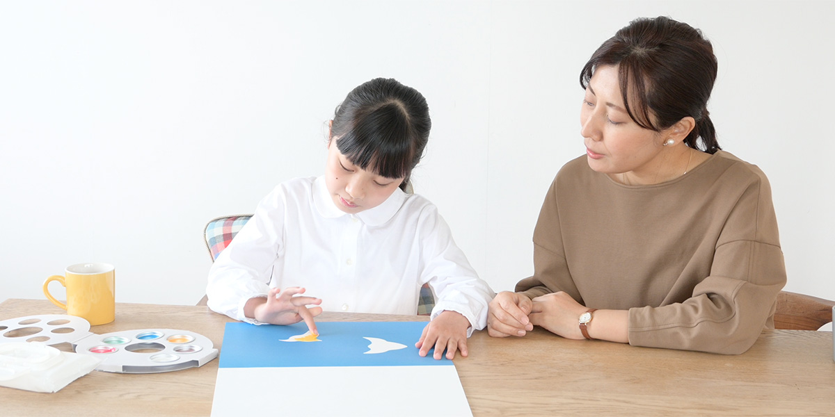 子供のお絵描きを親が見守っている様子